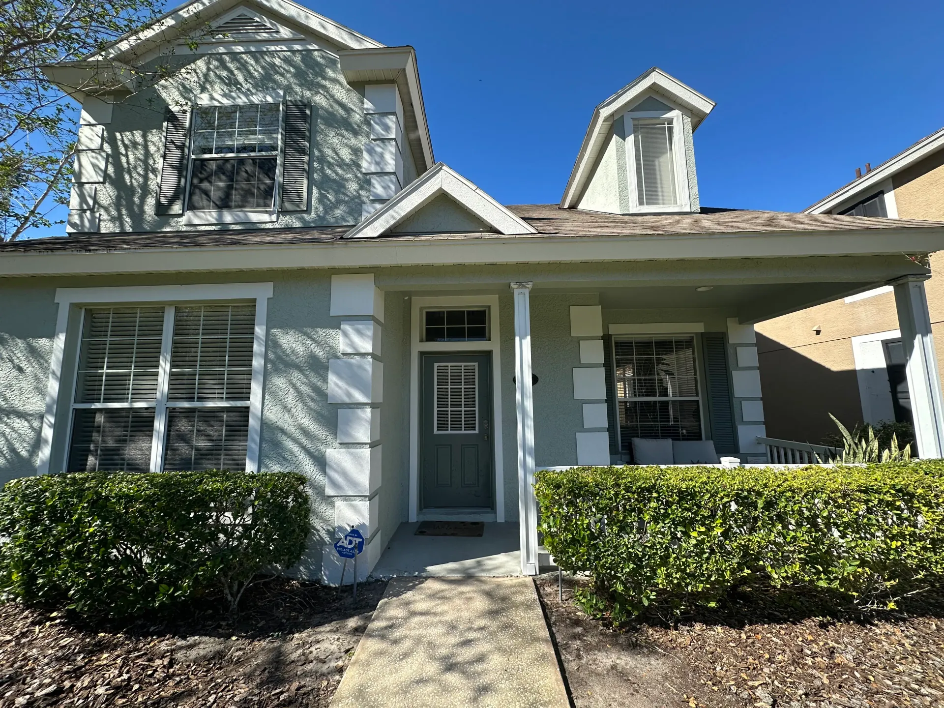Green stucco Pinellas County home with white trim and a front porch